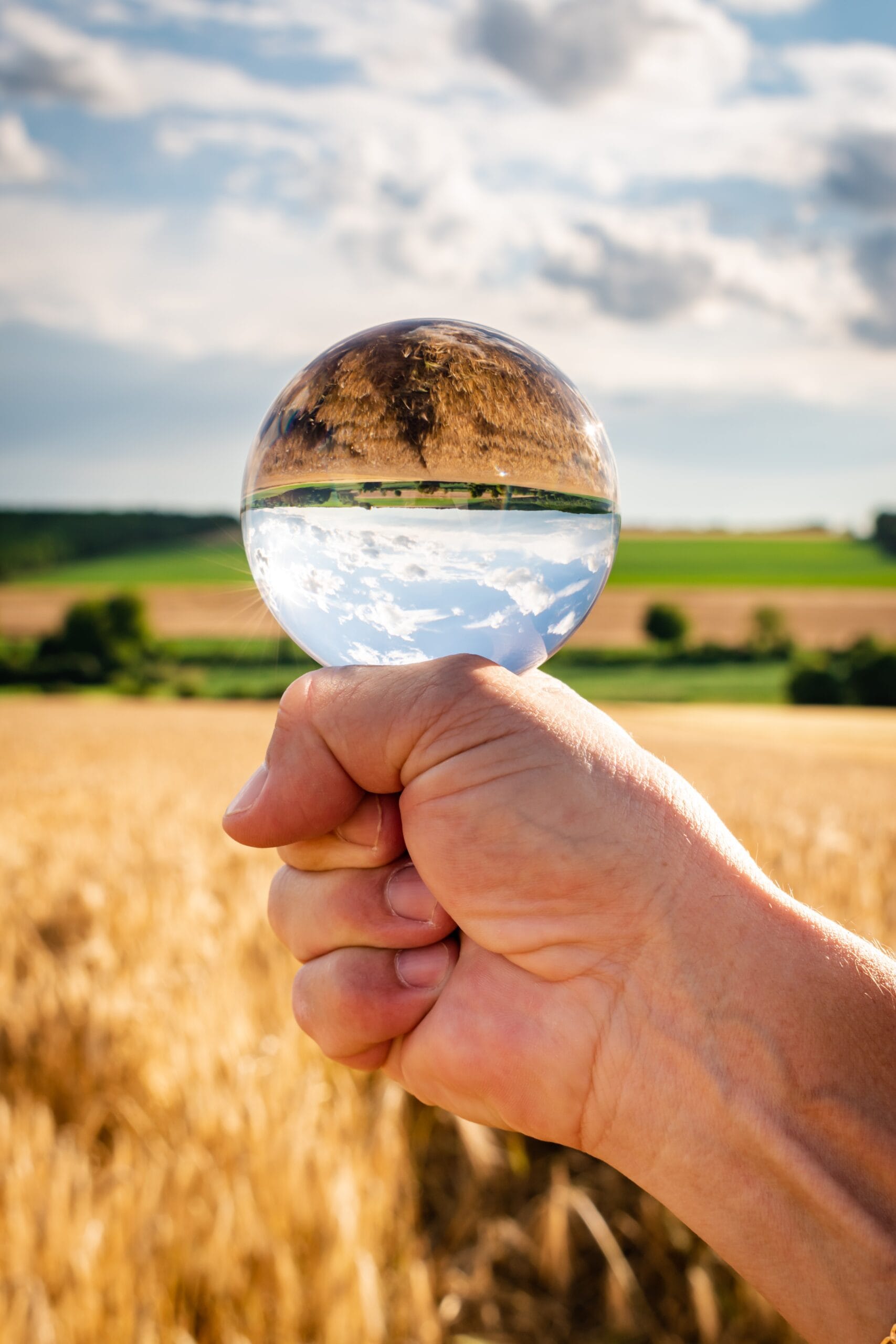 Observar 360 - Esfera de vidro sobre mão observando a paisagem: a imagem na esfera fica invertida.